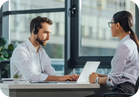 Two people communicating at a meeting with a laptop and headset