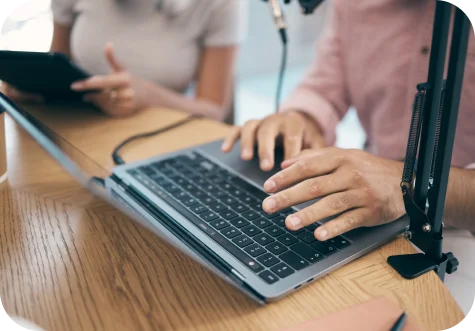 Typing on a laptop beside a microphone