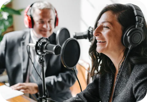 Two people recording a podcast with headphones and microphones