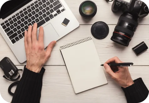 Taking notes beside a laptop and camera